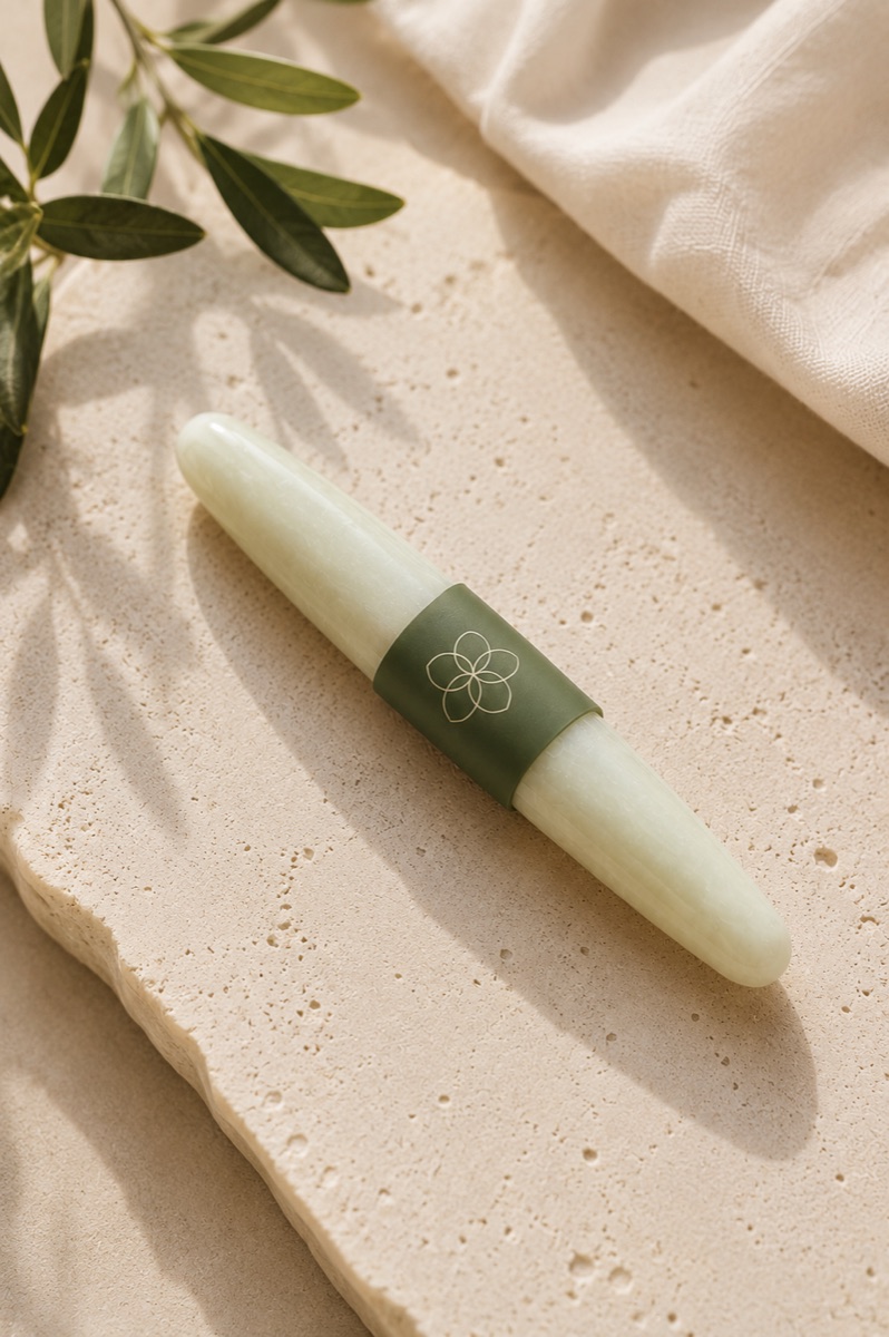 Flor Femme botanical wand resting on stone beside olive leaves